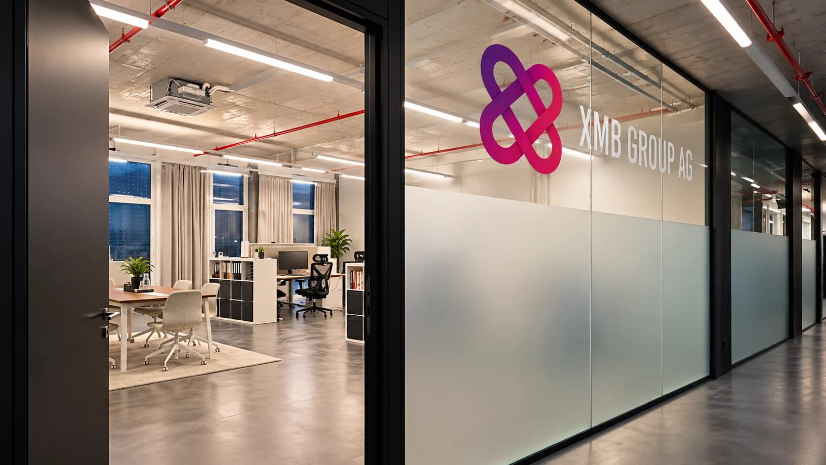 Eingang zum XMB Office mit Logo auf der Glaswand und Blick auf die Arbeitsplätze.